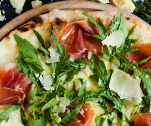 Pizza with procuito, arugula and parmesan
